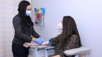 Clinician speaks with patient, while both wear face masks.